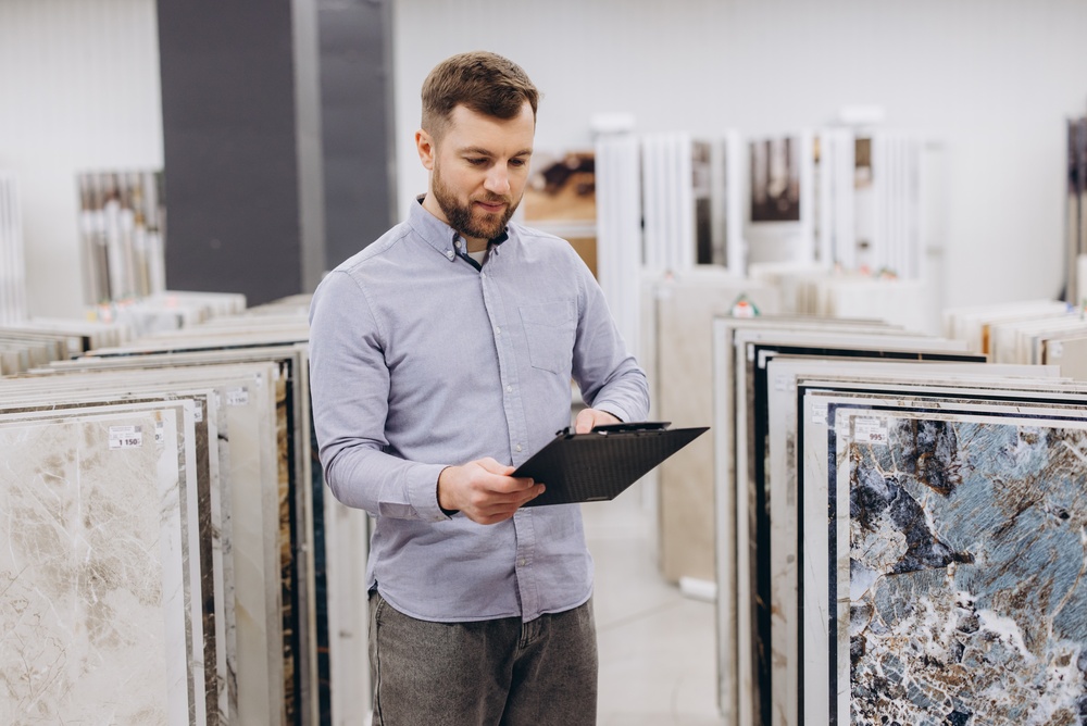Muškarac u salonu razgleda uzorke keramičkih pločica i beleži karakteristike dezena i teksture