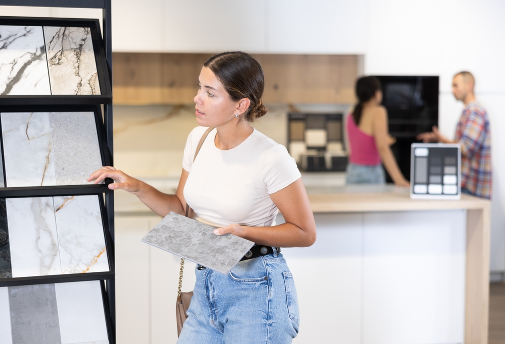 Žena bira keramičke pločice u salonu dok upoređuje uzorke različitih boja i tekstura